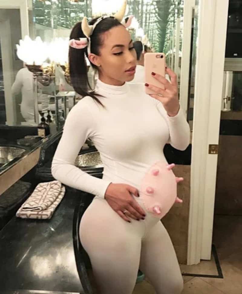 Woman in white bodysuit with pig-themed pregnancy costume, taking mirror selfie.