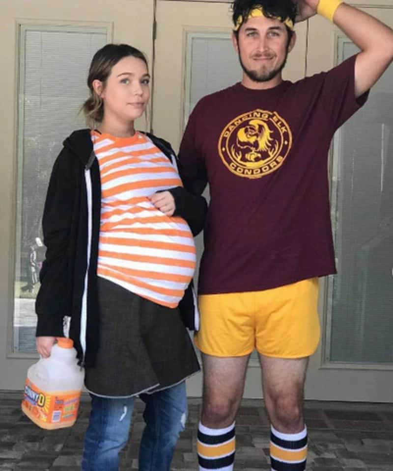 Pregnant woman and man in humorous costumes, woman with pregnant belly, man with yellow shorts and a.