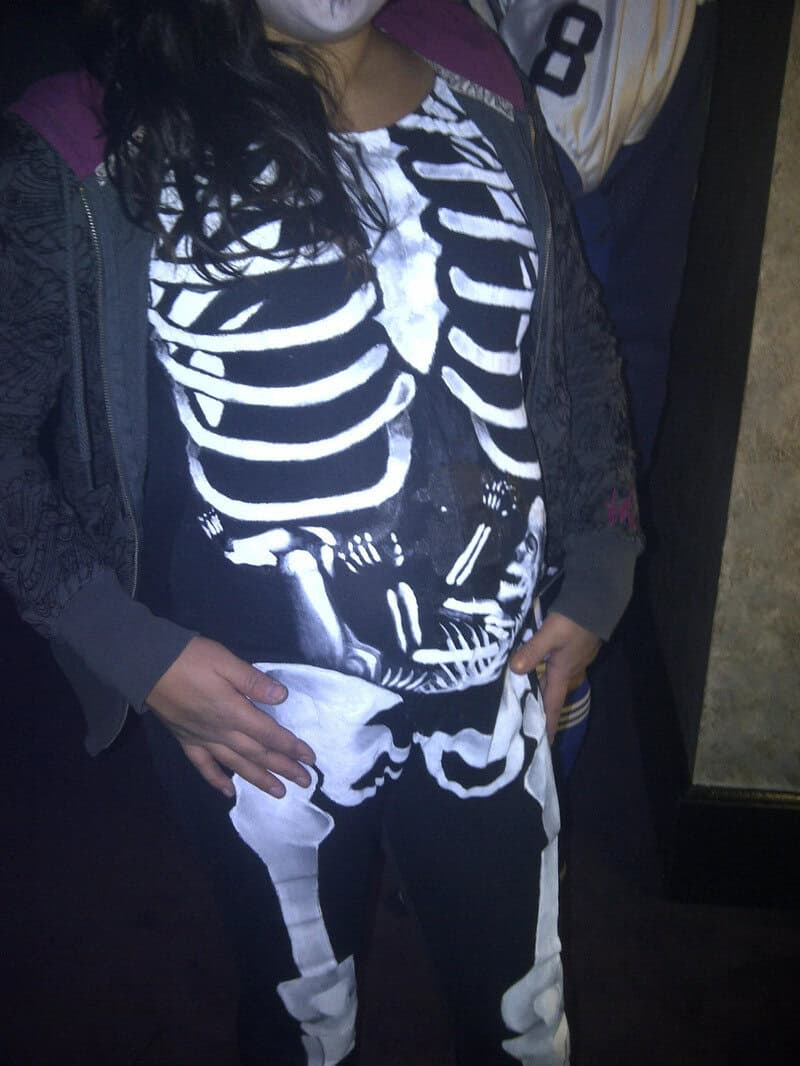 Person wearing skeleton costume with baby bump, matching skeleton design.