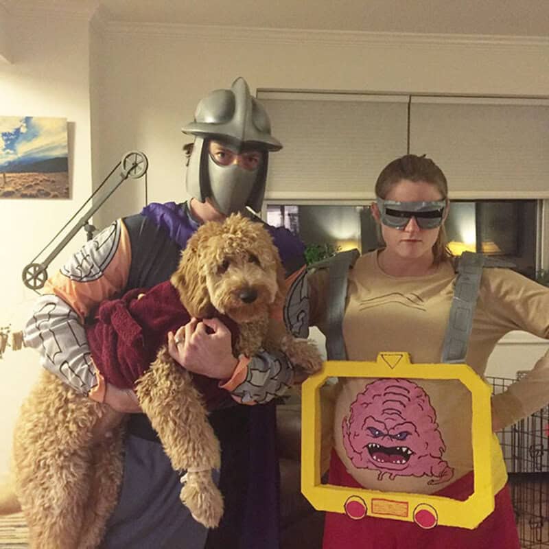 People in costumes with a dog, one dressed as a knight, another as a robot, and a dog in a red cape.