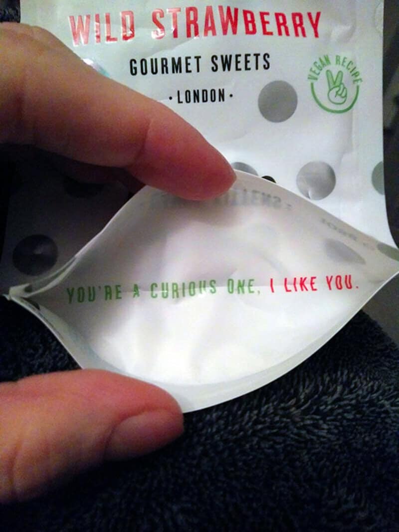 Close-up of a hand holding a white package with red and green text.