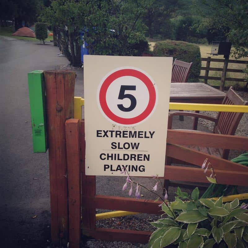 5 extremely slow children playing sign at park entrance.
