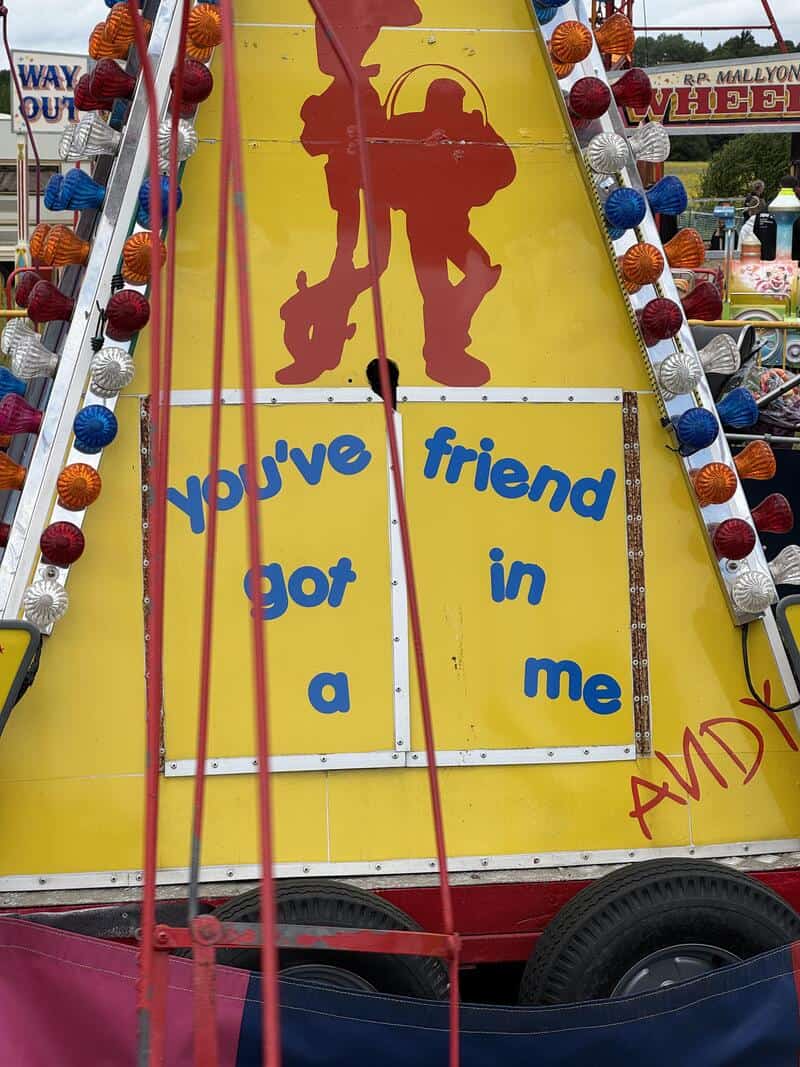 You've friend got in me sign on yellow carnival ride with silhouette and colorful lights.