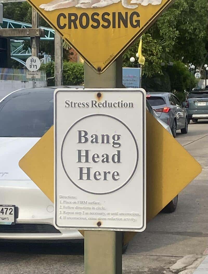Crossing sign with 'Bang Head Here' instruction on a circular target and 'Stress Reduction' text, on.