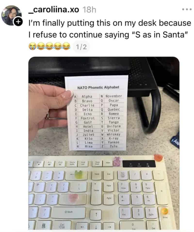 Photo of a hand holding a NATO phonetic alphabet chart above a keyboard.