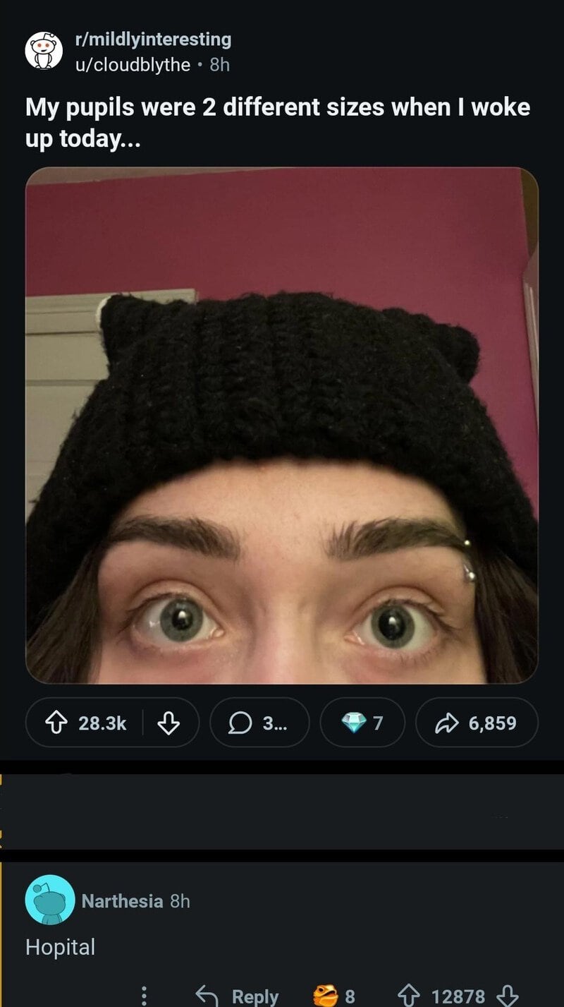Close-up of a person's eyes and forehead, wearing a black knit hat, with a pink wall in the背景.