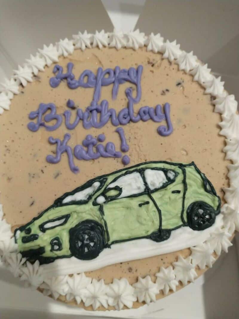 Happy Birthday Katie! Green car cake with purple text and white frosting border.