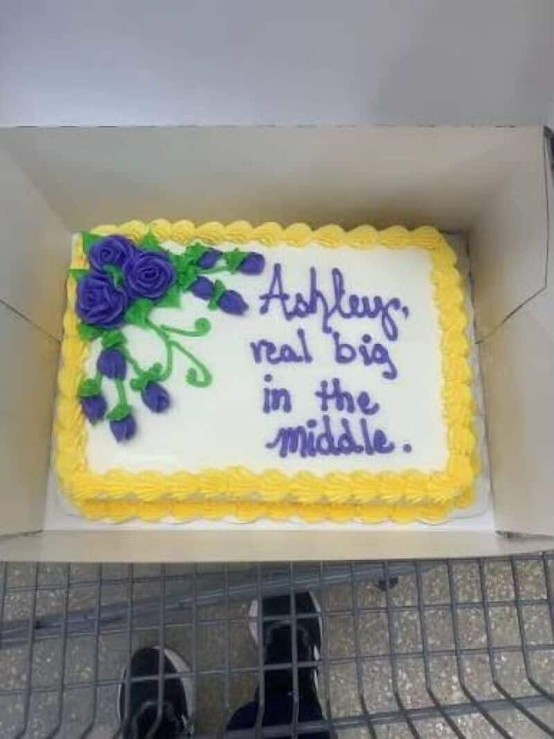 Hilarious cake with purple roses and green leaves, text: Ashley, real big in the middle. yellow and紫.