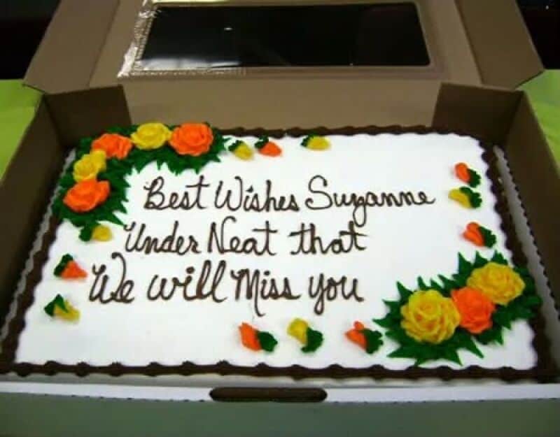 Best Wishes Suganne Under Neat that We will Miss you cake message with orange and yellow flowers.
