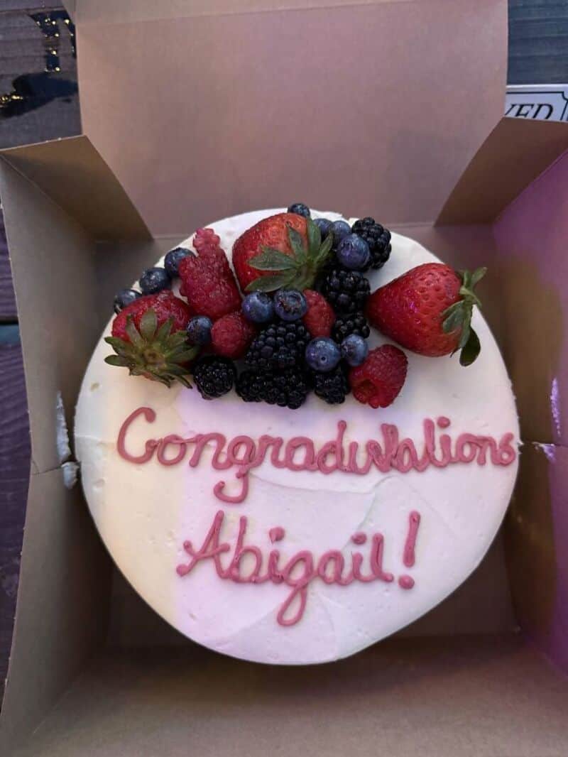 A round cake with white frosting topped with strawberries, blueberries, raspberries, and black rasp;.