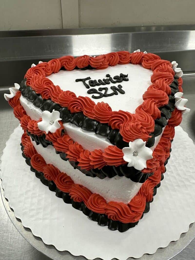 Hilarious cake with red and black ruffles and white flowers, text says 'Tastes SZN'.