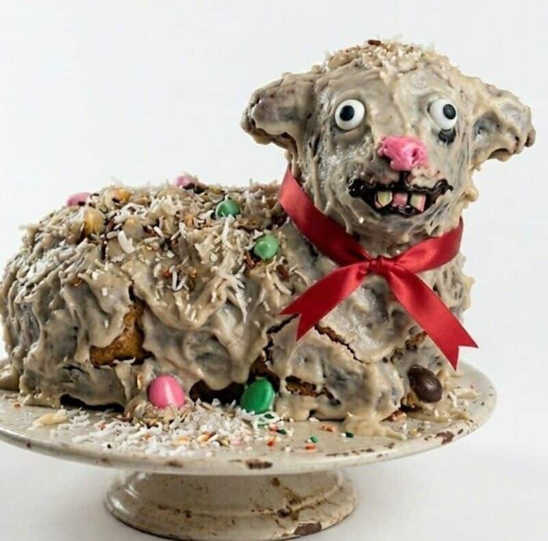Hilarious cake shaped like a melting dog with a red ribbon around its neck, colorful candies, and sh.