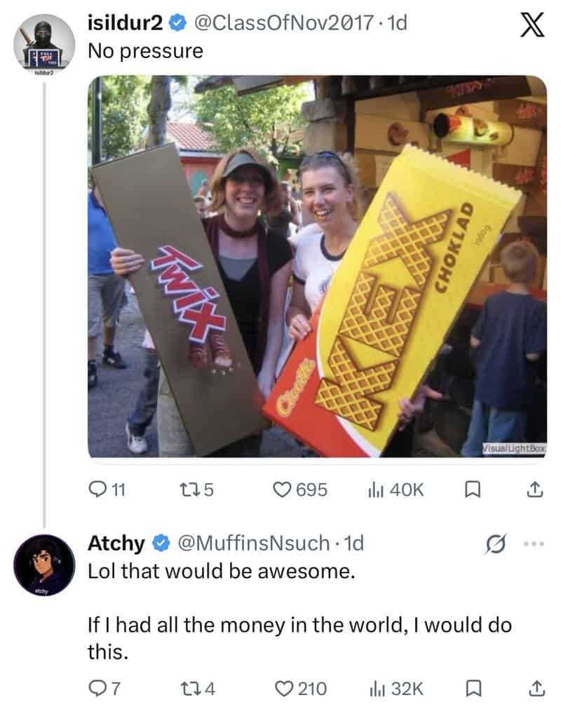 Two women holding oversized chocolate bar and waffle box, smiling at an outdoor event.