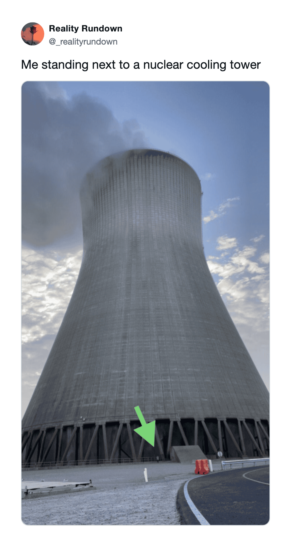 Standing next to a large nuclear cooling tower with a green arrow pointing at its base.