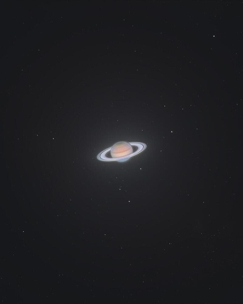 Saturn with rings and stars in space, dark background.