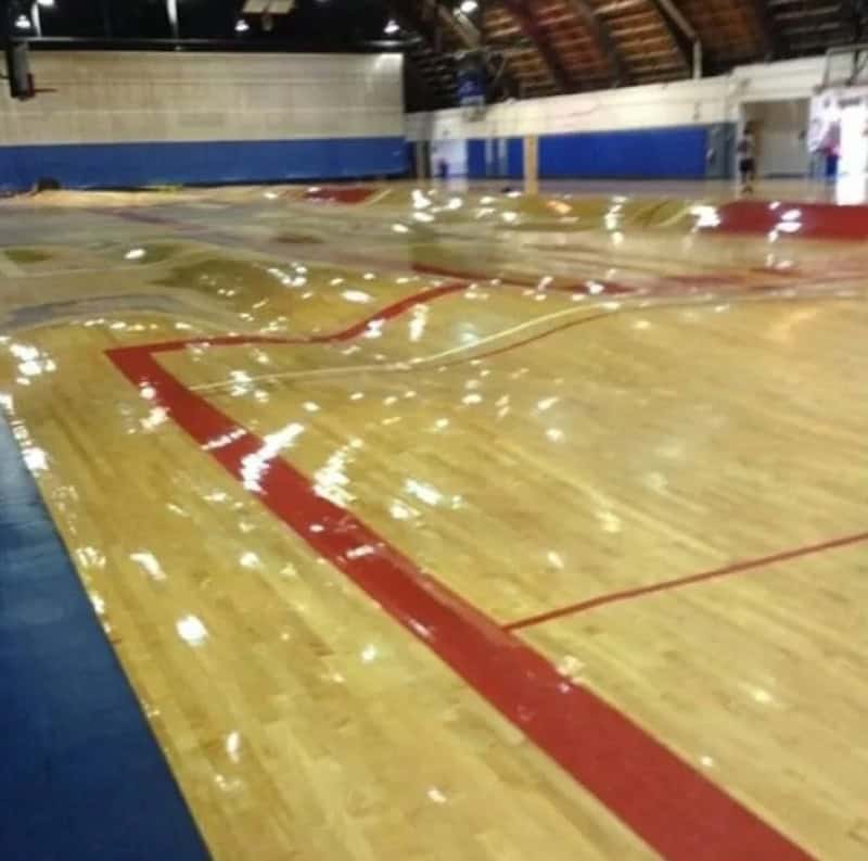 Indoor basketball court with polished wooden floor and red and white lines.