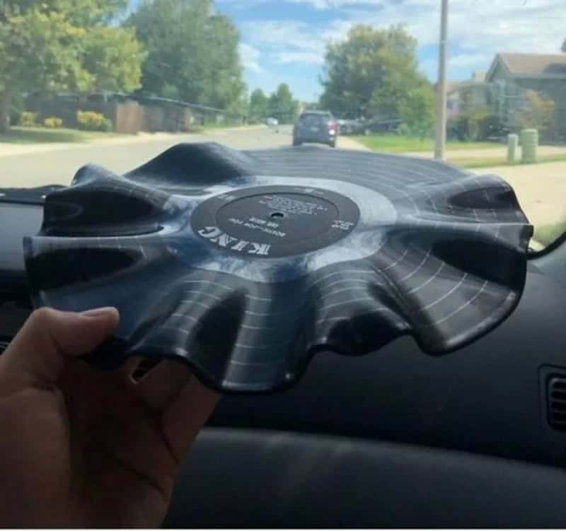 Person holding a vinyl record shaped like a flower inside a car.