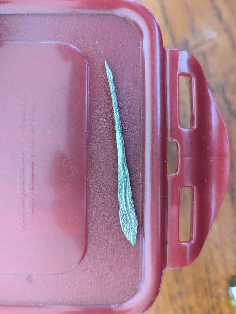 A close-up of a metallic tool with a textured handle on a red plastic surface.