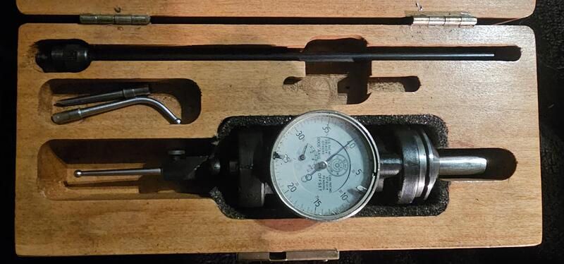 Dial indicator gauge with metal rods in a wooden box.