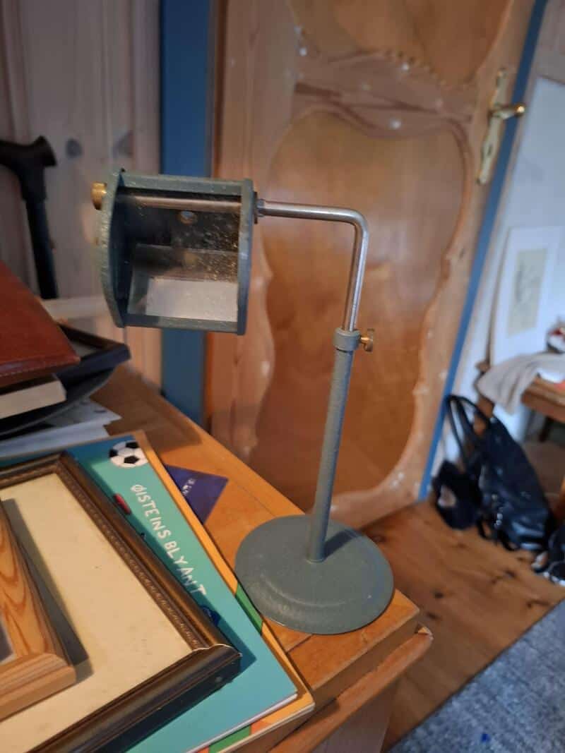 Small vintage desk lamp with a flexible arm on a wooden table.