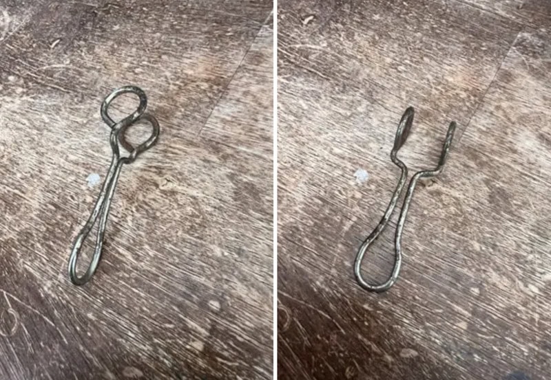 Two metal eyelash curlers on a wooden surface, one open and one closed.