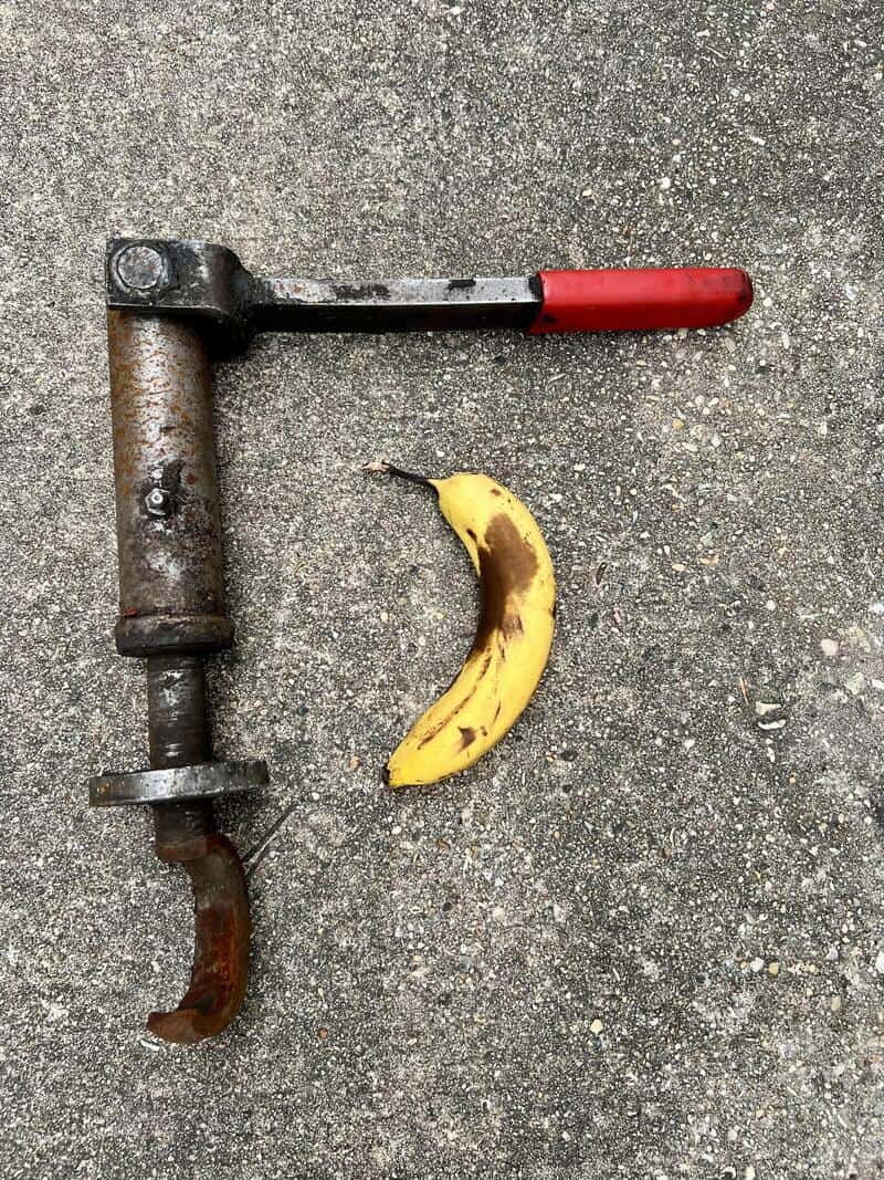 A rusty clamp and a yellow banana on a concrete surface.