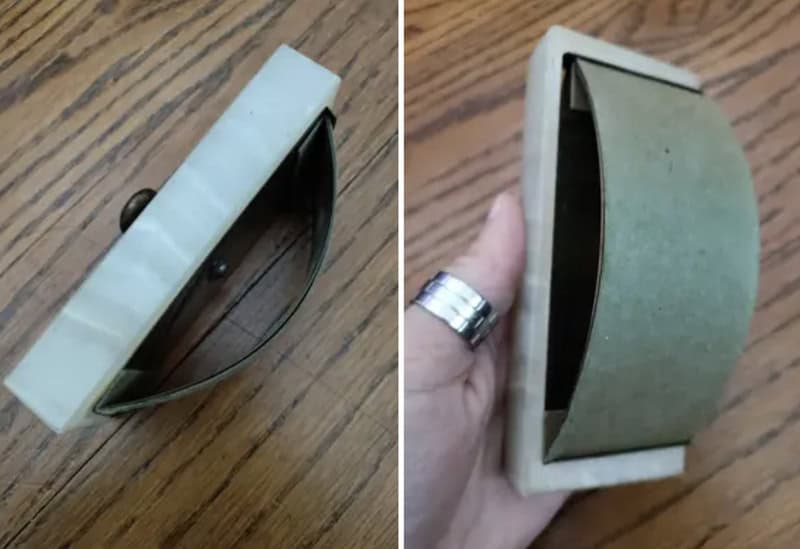 Vintage metal and plastic stapler with a curved design on a wooden surface.