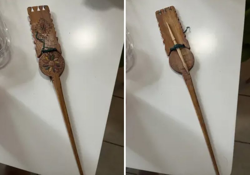 Decorative wooden hairbrush with floral design and a long handle.