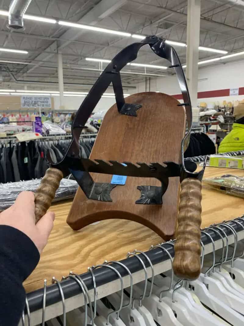 Vintage wooden and metal hand saw with wooden handles on a store table.