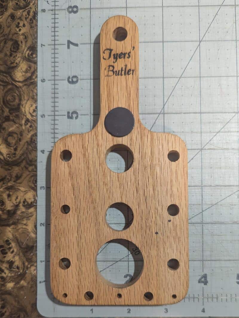 Wooden object with multiple holes and 'Tyers Butler' engraved on top.