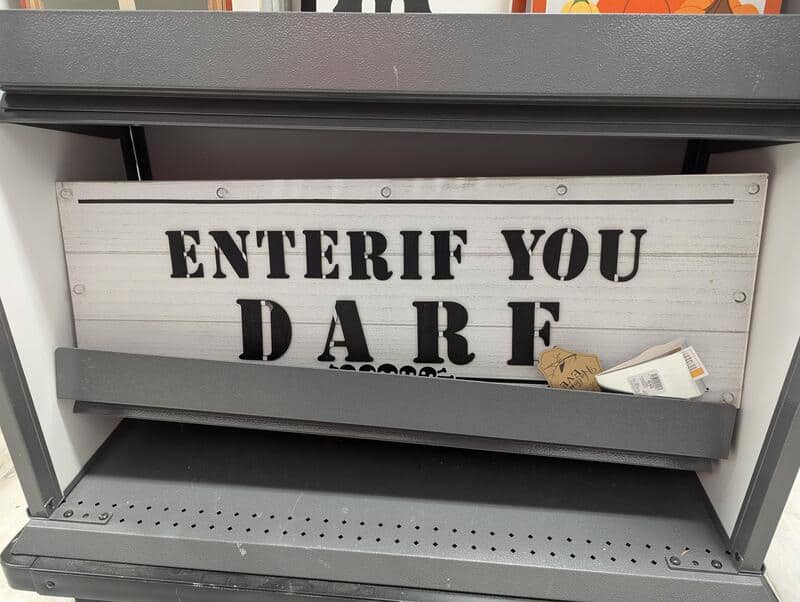 Sign reads 'ENTERIF YOU DARE' with a small paper and a tag on a shelf.