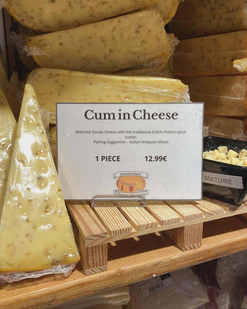 Cheese labeled 'Cum in Cheese' with a price of 12.99 euros, on a wooden shelf.