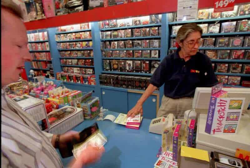 Customer at checkout in a store with shelves of products in the background.