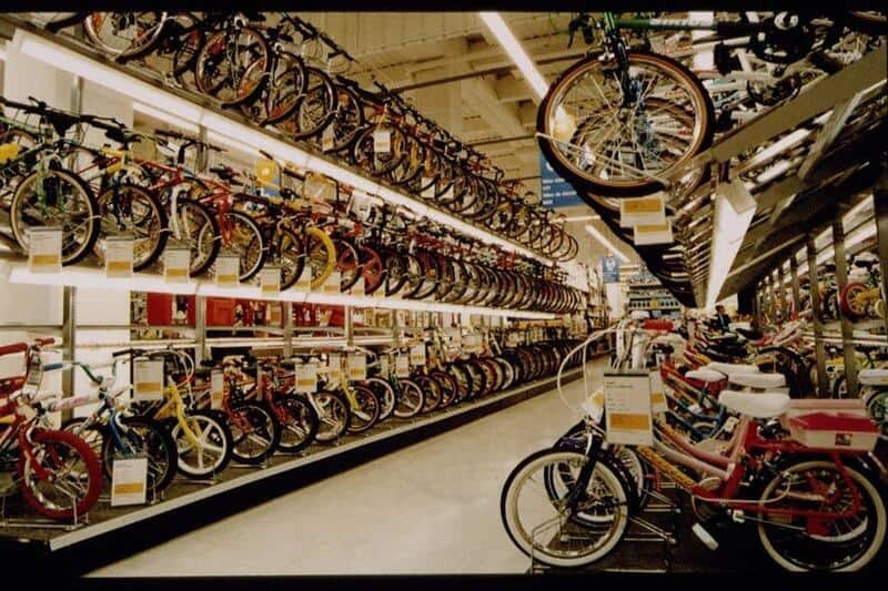 Vintage bicycle shop with rows of bikes on display, including hanging cycles and stacked shelves.