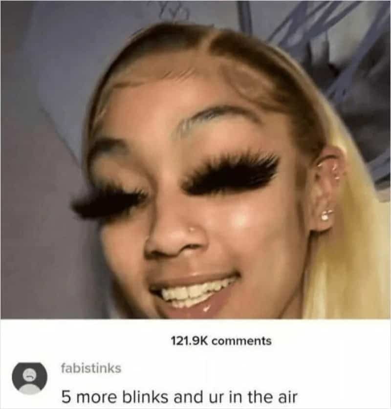 Close-up of a woman with long false eyelashes, blonde hair, and multiple earrings.
