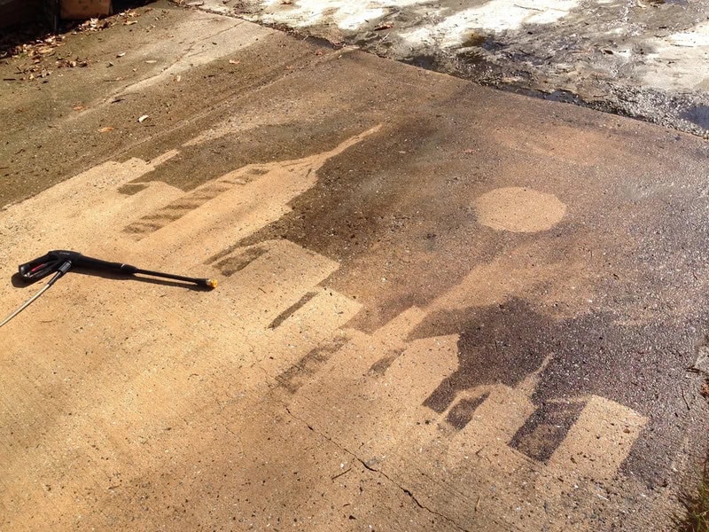 Power washing a concrete driveway, showing before and after cleaning areas.