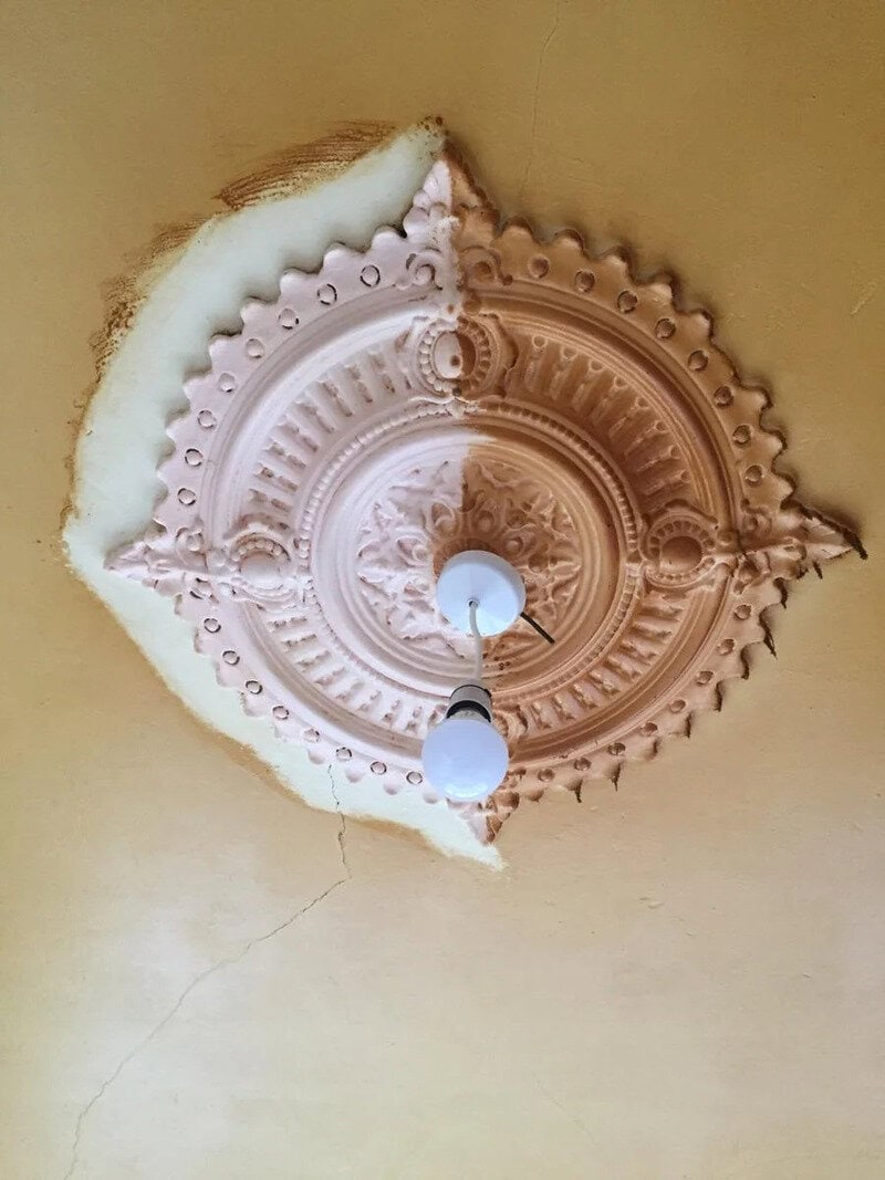 Ceiling light fixture with ornate design, partially damaged with exposed insulation.