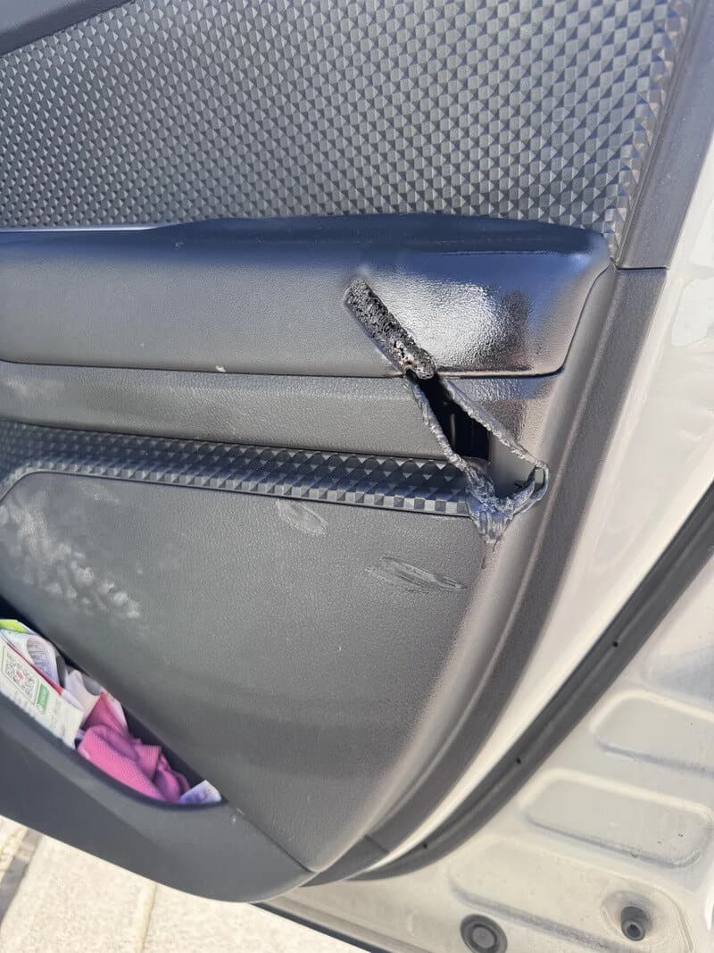 Car door with a broken handle and ice buildup, door panel damaged.
