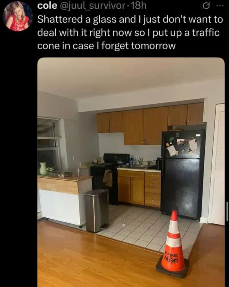 Shattered cabinet and damaged kitchen area with debris; orange traffic cone on tiled floor in front.