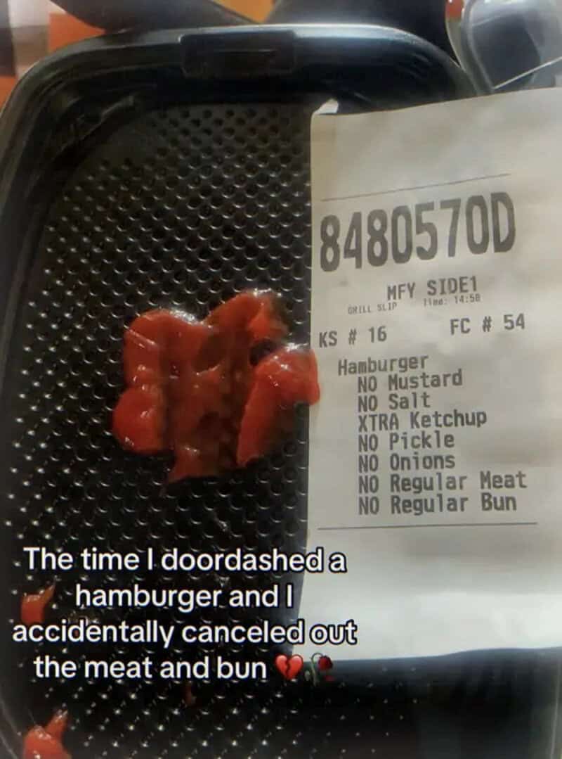 Receipt and a small burger bun with ketchup on a black tray.