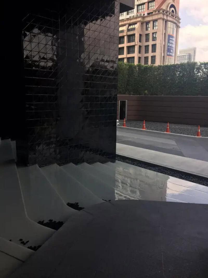 Black tiled wall with stairs and a city view outside.