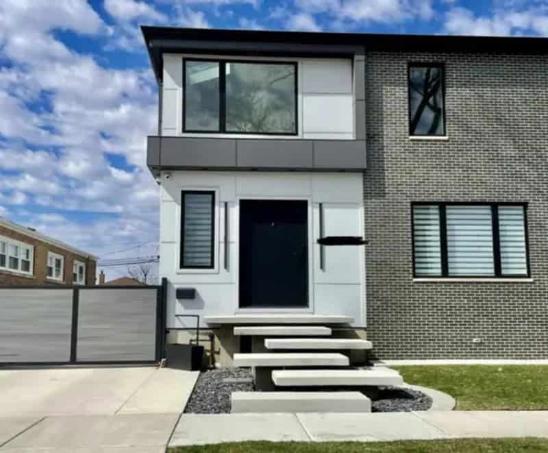 Modern house with stairs leading to the front door, no handrails, and a black mailbox.