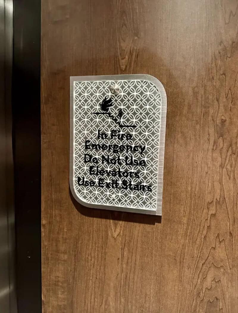 Sign with a pattern and text that is difficult to read, mounted on a wooden wall.