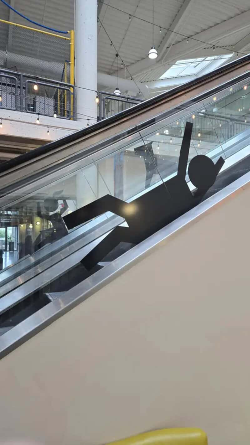 Person falling down an escalator in a shopping mall.