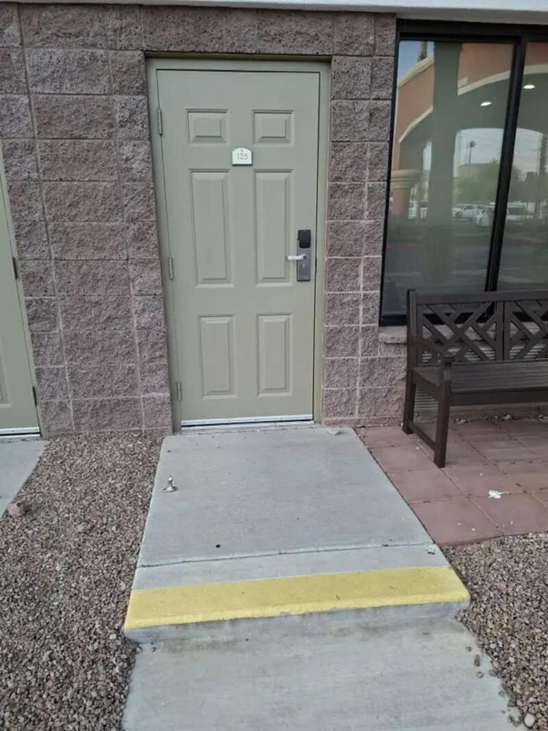 Door with a ramp and a yellow warning strip at the entrance.
