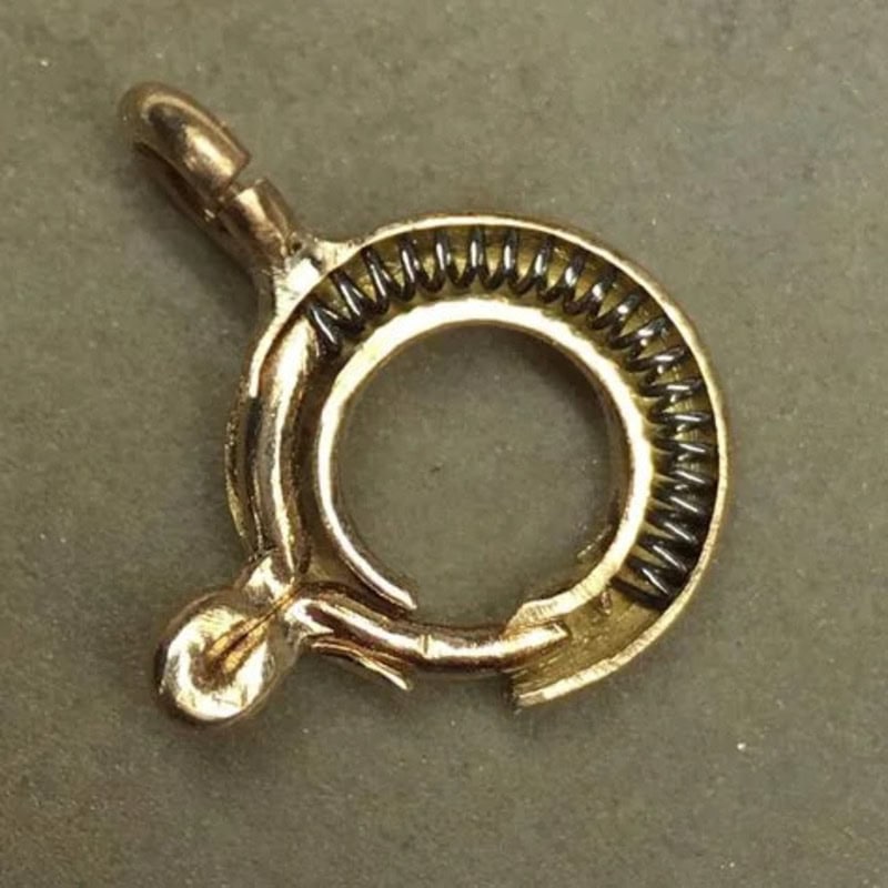 Close-up of a metallic spring clasp with a small ball at one end.