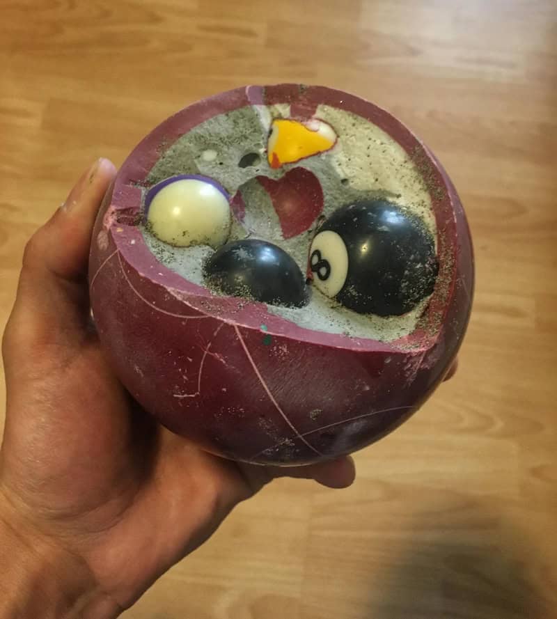 Broken pool ball set in a spherical container with a hand holding it.