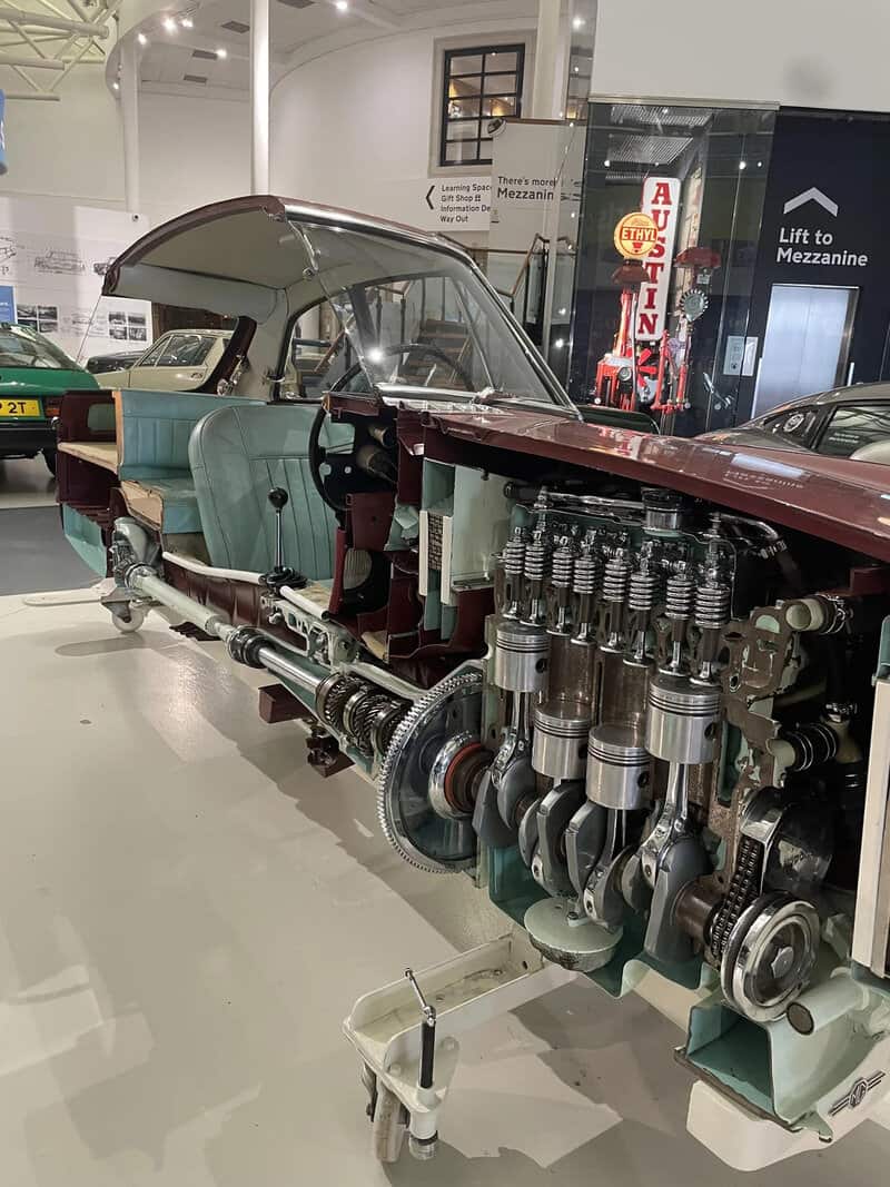 Cross-section of a vintage car showing engine and interior details at a museum.