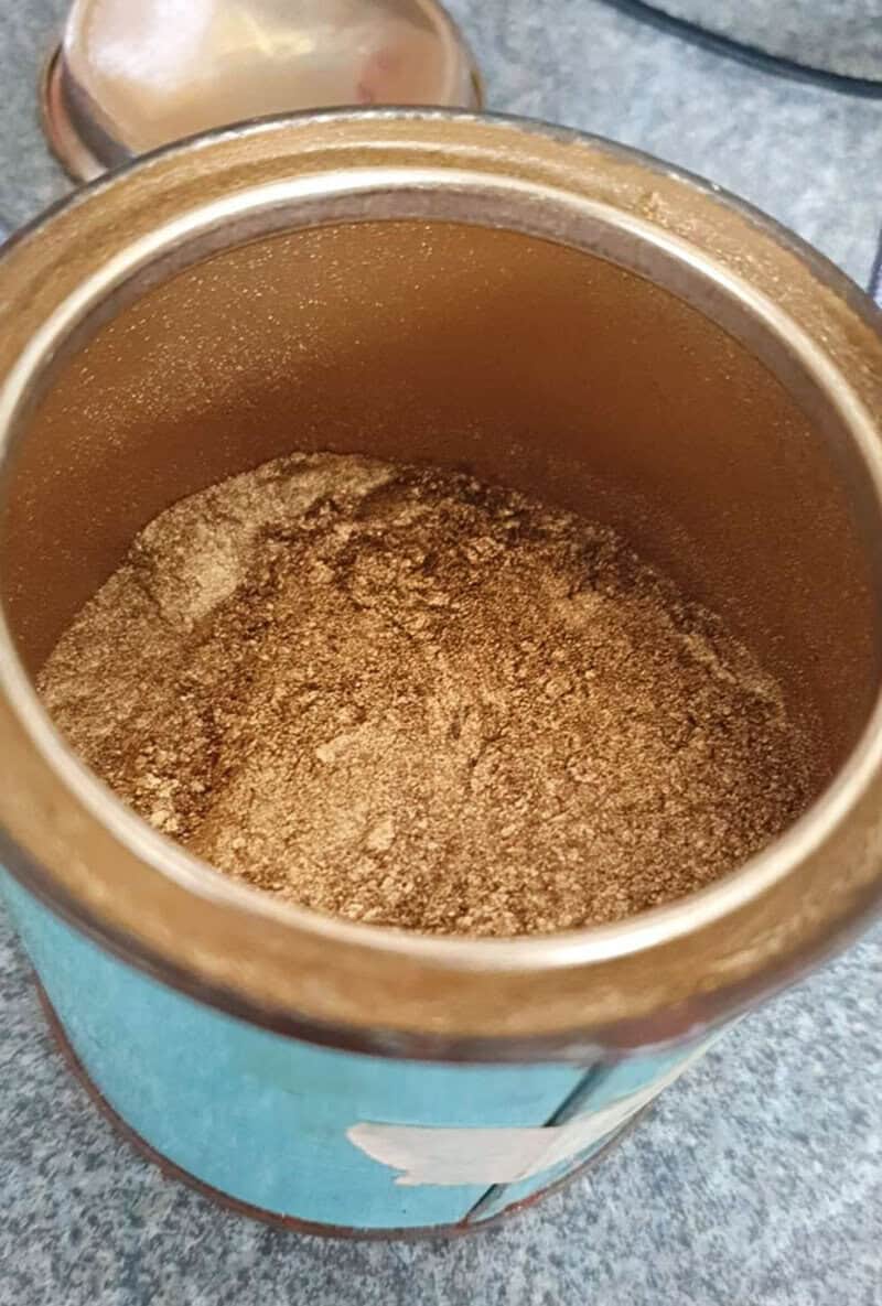 Open tin of ground spices on a kitchen counter.