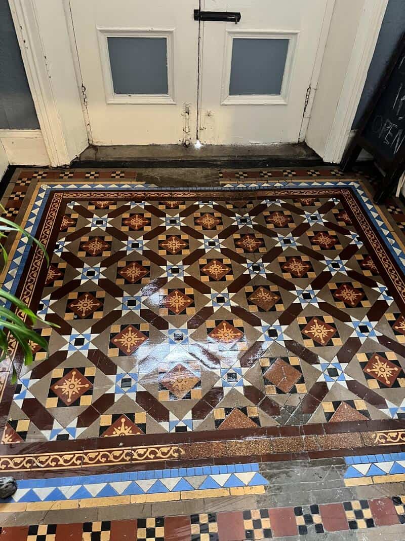 Colorful vintage tiled floor in front of a white door with glass panels.